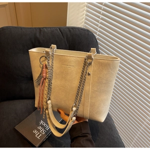 Detail of beige tote bag with chain strap and fashion logo on corduroy background