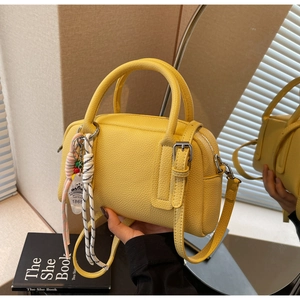 Close-up of bright yellow Boston bag featuring lychee texture and fine metal hardware
