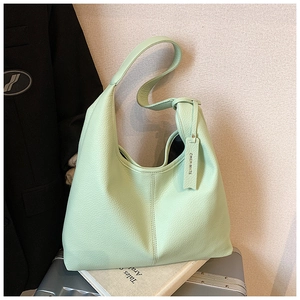 Detail of mint green lychee grain leather hobo bag with wide strap and branded tag
