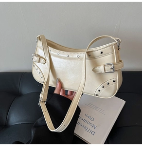 Détail du sac à bandoulière en similicuir beige avec des rivets et boucles argentés