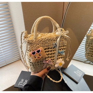 Detail of woven bucket bag featuring cute bear charms, satin bows and star pendants
