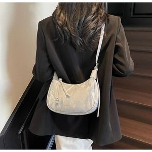 White crescent crossbody bag with marble texture and side tassels shown on model