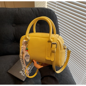 Detail of yellow lychee pattern handbag with silver hardware and decorative charm