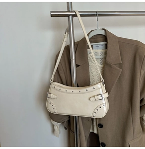 Détail du sac à bandoulière blanc crème en similicuir avec des rivets argentés et boucles