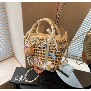 Detail of beige woven bucket bag with bear and floral charms for beach vacation