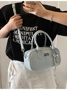 Light blue Boston handbag with metallic bow charm and silver plaque in minimalist style