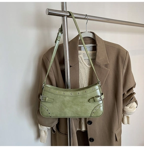 Détail du sac sous le bras en PU vert avocat avec rivets argentés sur un cintre minimaliste