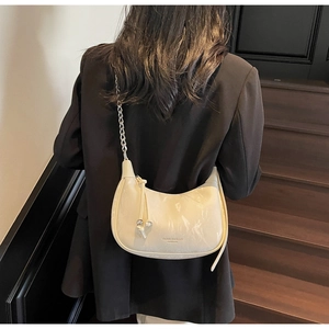 Close-up of beige half-moon shoulder bag with glossy crinkle leather and silver chain