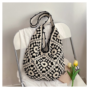 Detailed close-up of handmade crochet hobo bag with black and white floral square patterns