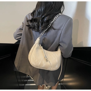 Detail of off-white crossbody bag with silver chain and marble texture on beige leather