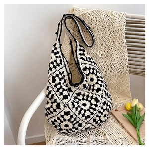 Detail of hand-crocheted black and white floral pattern on a vintage style hobo tote bag