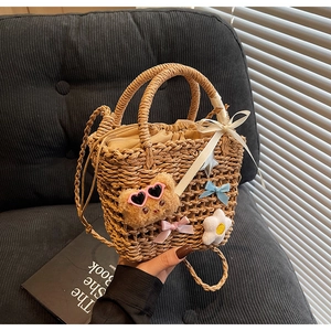 Close-up of woven bucket bag featuring cute bear plush and decorative silk ribbons