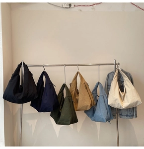 Selection of large nylon tote bags in various colors hanging on a retail rack for display