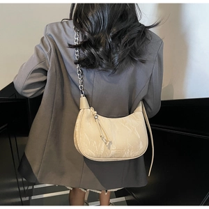 Detail view of beige half-moon hobo bag with unique crackle texture and metal chain