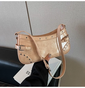 Détail du sac baguette en cuir verni beige avec clous argentés et détails de boucle