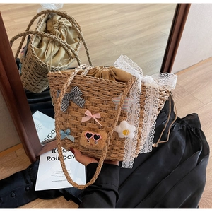 Détails du sac seau en paille avec nœud en dentelle et décoration d'ours en peluche