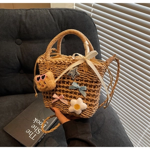 Detail of woven straw bucket bag with teddy bear pendant and drawstring lining