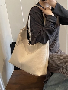 Fashionable beige pebbled leather hobo tote bag for women in a minimalist indoor setting