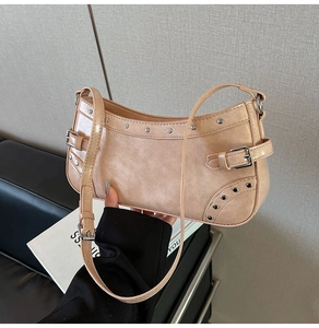 Gros plan d'un sac à bandoulière rose nude en cuir brillant avec rivets argentés