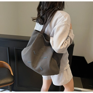 Detailed view of large canvas tote bag with contrast stitching and brown leather straps