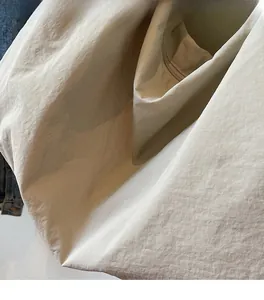 Detail of the cream nylon tote bag showing its interior zipper pocket and soft fabric texture