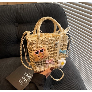 Detail of woven straw bucket bag with cute bear charm and white floral accents