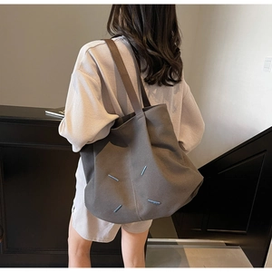 Detail showing the gray canvas tote bag back with four blue minimalist stitch accents