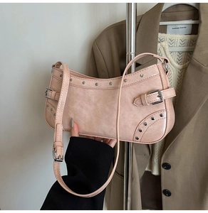 Détail du sac baguette rose pâle montrant les rivets argentés et la texture du similicuir
