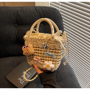 Detail of straw bucket bag with plush bear charm and ribbon decor for beach vacations