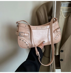 Détail du sac baguette rose avec rivets argentés et boucle sur une surface texturée