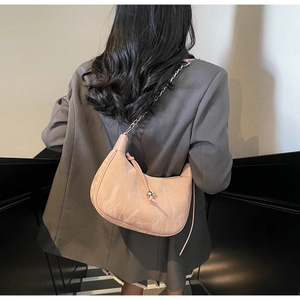 Detail showing the pink dumpling-shaped underarm bag with silver chain and logo