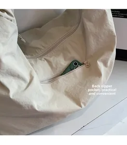 Close-up of the beige nylon tote bag featuring a functional back zipper pocket for a phone