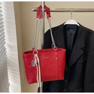 Detail of red leather tote bag with silver chain strap and tennis racket charm