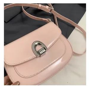 Détail du sac selle en cuir verni rose avec boucle argentée polie en forme de U