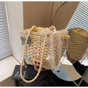 Détail du sac seau en paille avec nœuds mignons, breloque ours et bordure en dentelle