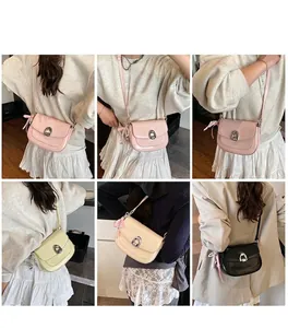 Détail de sacs selle en cuir verni avec breloques en perles et boucles métalliques