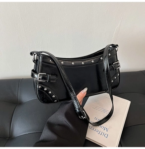 Vue détaillée du sac sous le bras en similicuir noir avec rivets argentés et boucle