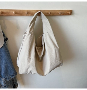 Close-up of beige oversized tote bag made of durable nylon hanging on a wooden hook