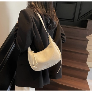 Close-up of a cream-colored half-moon hobo bag with knotted details on a model