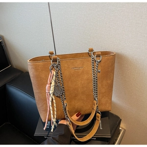 Close-up of brown PU leather tote bag with silver chain strap and decorative charms
