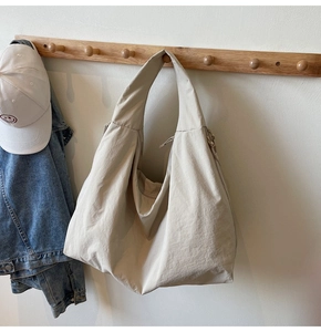 Macro detail of beige nylon hobo bag featuring premium texture and wide shoulder strap