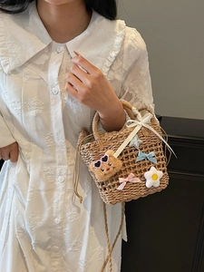 Woven straw bucket bag with cute bear charm and ribbons for summer beach vacations