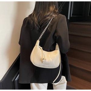 Detail of a creamy white half-moon crossbody bag with glossy faux marble texture and chain