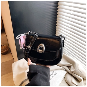 Détail du sac selle en cuir verni noir brillant avec boucle argentée et perles