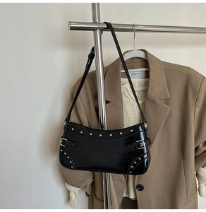 Détail d'un sac porté épaule noir vintage avec rivets argentés et boucles métalliques