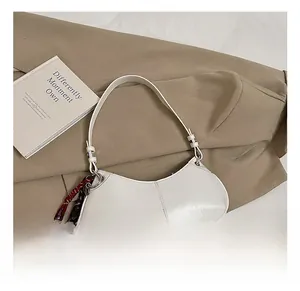 Detail shot of a white oil wax leather shoulder bag with a brown braided strap detail