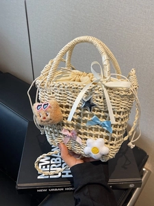 Handwoven straw bucket bag with cute bear charm and decorative bows for beach travel