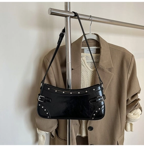 Détail du sac bandoulière en cuir noir brillant avec rivets argentés et boucle métallique