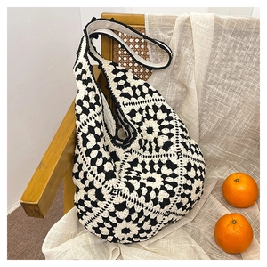 Detail of crochet tote bag with black and white floral pattern on a rattan chair
