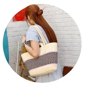 Detailed close-up of a beige woven tote bag with a pink and monochrome stripe accent